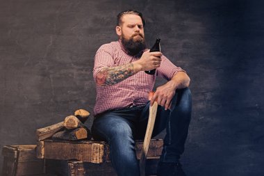 Adam bir bira şişesi ve balta tutar