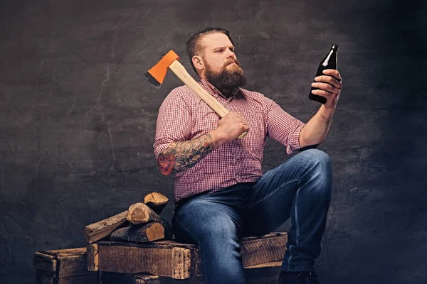 Man holds a beer bottle and axe — Stock Photo, Image