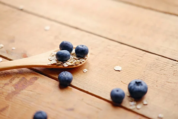 Wooden spoon with oat flakes and blueberries — Stock Photo, Image