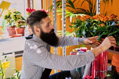 Bir çiçekçi dükkanı sakallı dövmeli adam