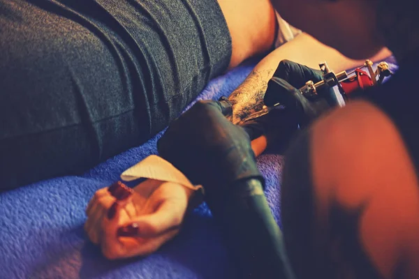 Att göra en tatuering på en kvinnas arm. — Stockfoto