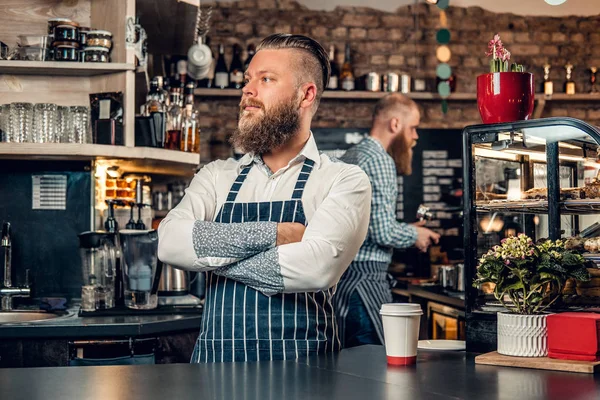 大胡子咖啡师男性，双臂交叉，在酒吧站在一杯咖啡 — 图库照片