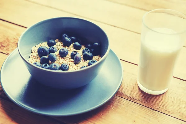 Oat flakes with blueberry in a blue cup on a wooden table. — Stock Photo, Image