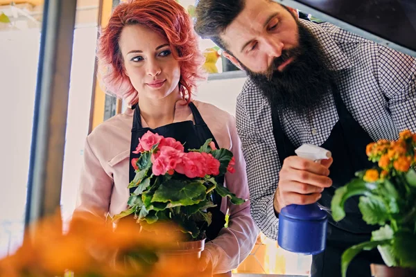 Man and woman watering flowers