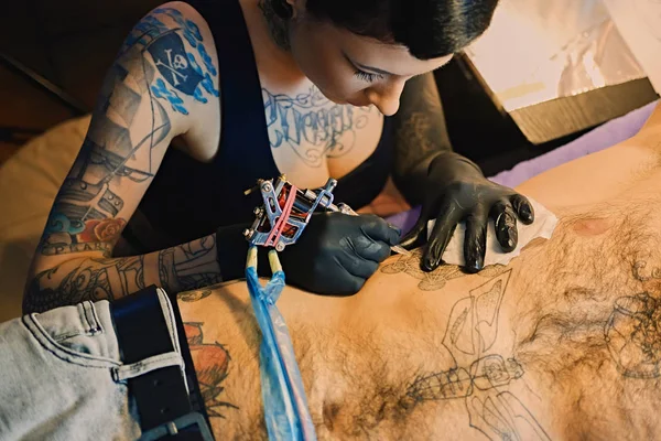 Female tattoo artist makes a tattoo