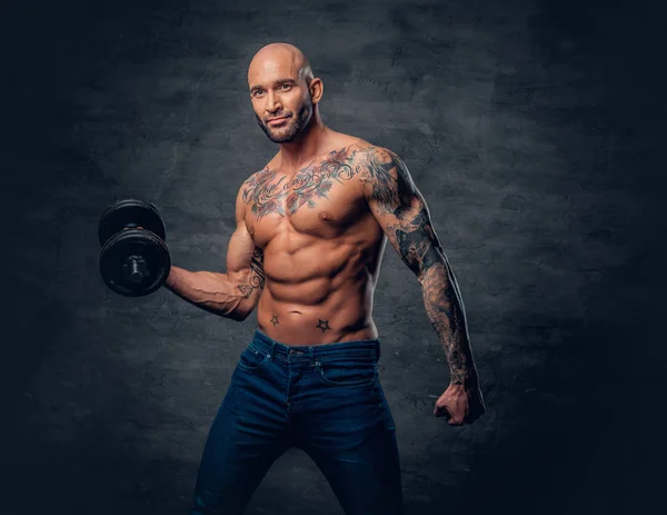 Brutal man with tattoos holds dumbbell — Stock Photo, Image