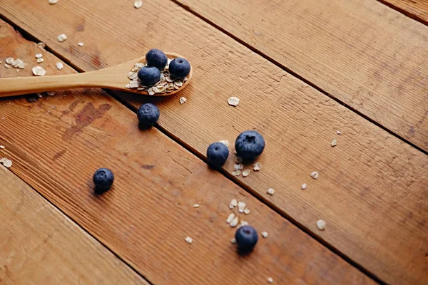 Wooden spoon with oat flakes and blueberries — Stock Photo, Image