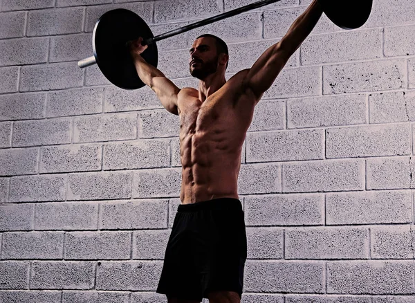 Athletic shirtless man holds a barbell — Stock Photo, Image
