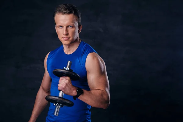 Hombre en una ropa deportiva azul sostiene la mancuerna — Foto de Stock