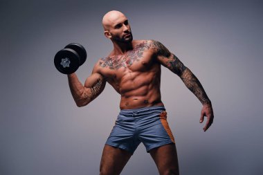 Atletik erkek dövmeli dumbbell tutar