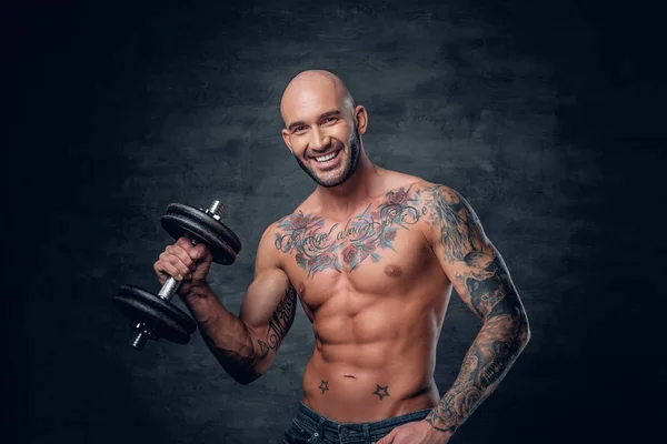 Deportivo hombre con tatuajes sostiene mancuerna — Foto de Stock