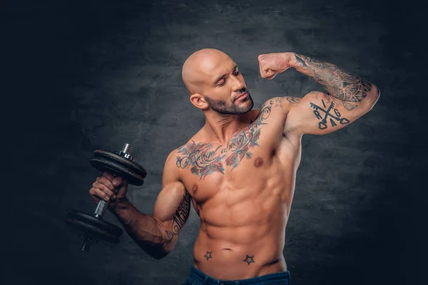 Sporty man with tattoos holds dumbbell — Stock Photo, Image