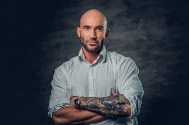 Dövmeli çapraz kolları olan Beyaz tişörtlü adam.