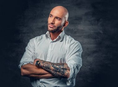 Dövmeli çapraz kolları olan Beyaz tişörtlü adam.