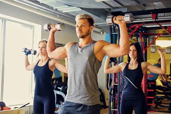 Athletic man and two slim women — Stock Photo, Image