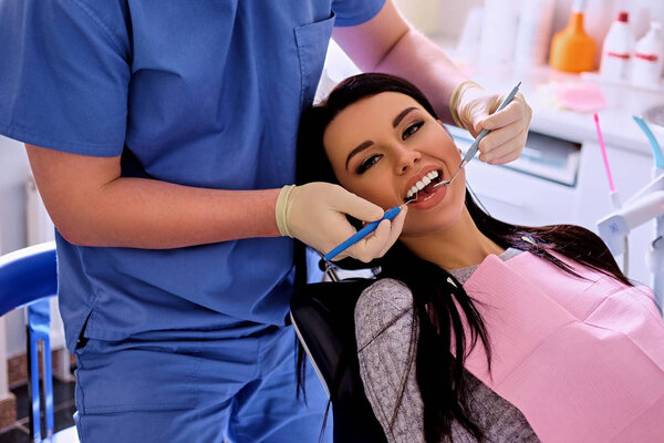 Dentist examining female's teeth 