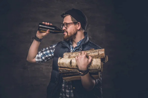 Człowiek posiada drewno opałowe i piwo butelkowe — Zdjęcie stockowe