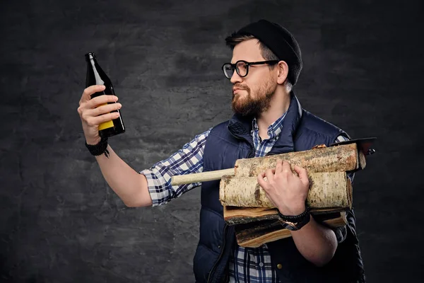 Homem detém lenha e cerveja engarrafada — Fotografia de Stock