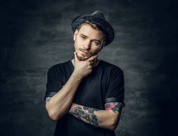 Thoughtful male with crossed tattooed arms