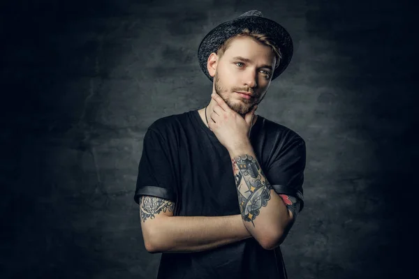 Thoughtful male with crossed tattooed arms