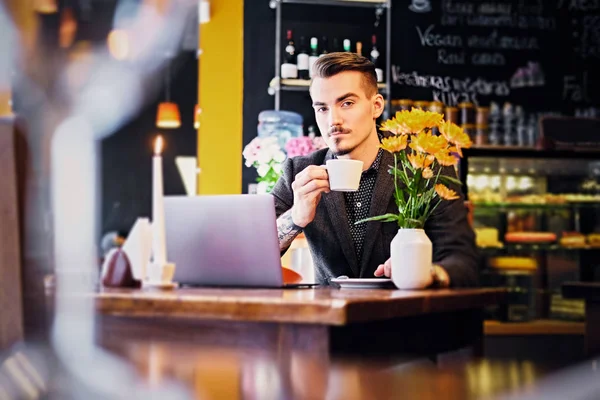 Man drinks coffee and using laptop