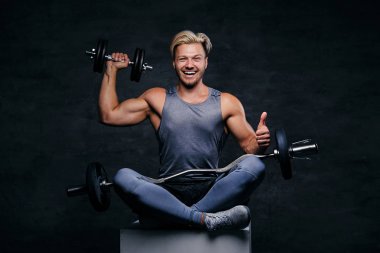 Sarışın sportif erkek halter seti tutar