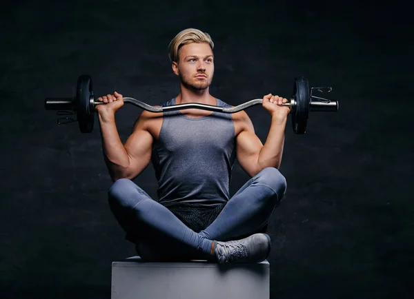 Blond sporty male holds barbell