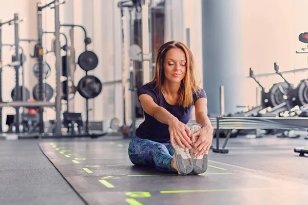 Athletische Frau dehnt sich in einem Fitnessstudio — Stockfoto