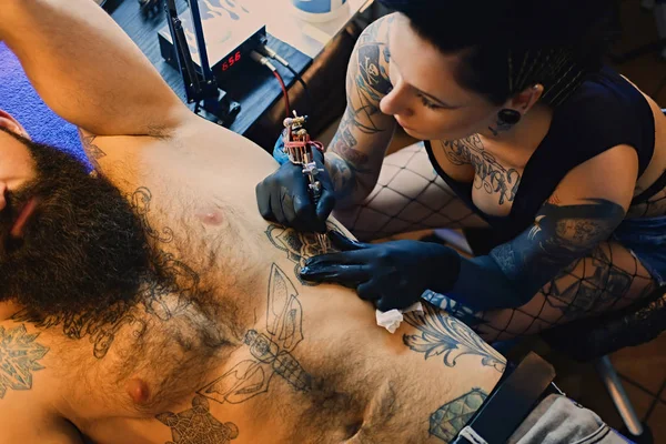 Tatuaje artista hace tatuaje en torso masculino — Foto de Stock