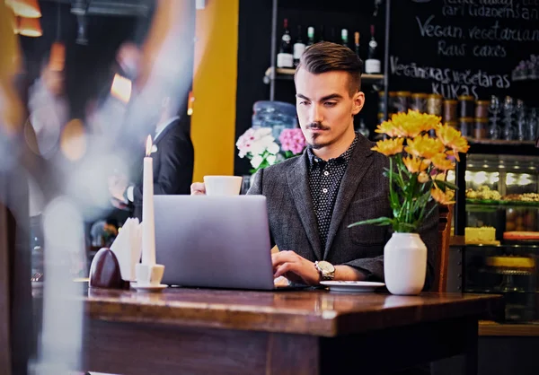 Ο άνθρωπος χρησιμοποιώντας φορητό υπολογιστή σε ένα καφέ — Φωτογραφία Αρχείου