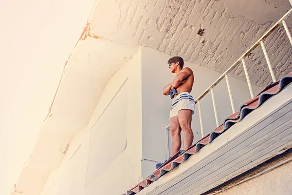 Shirtless rescuer looking through binocular — Stock Photo, Image