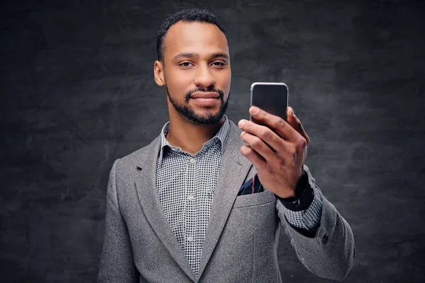 American male in a grey suit holds smartphone — Stock Photo, Image