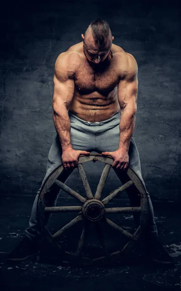 Stoere binken Gespierd / bodybuilder houdt houten wiel — Stockfoto