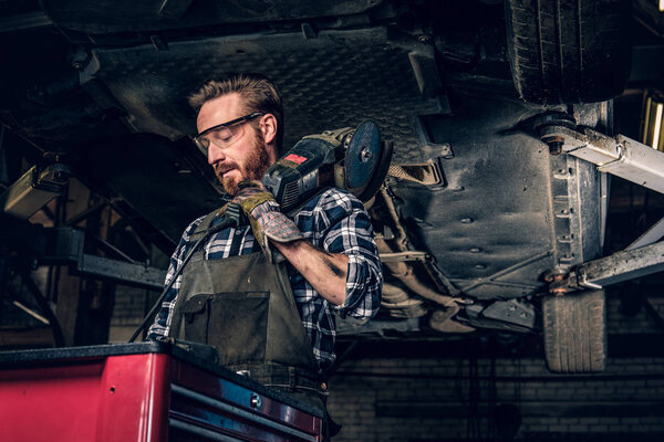 Mechanic holds angle grinder on a shoulder.