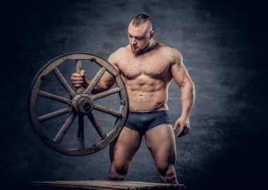 Vücut geliştirmeci eski ahşap tekerleği tutar 