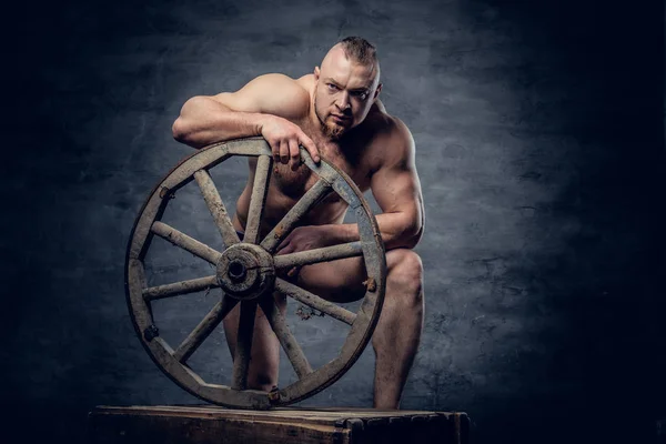 Чоловік позує зі старим дерев'яним колесом — стокове фото
