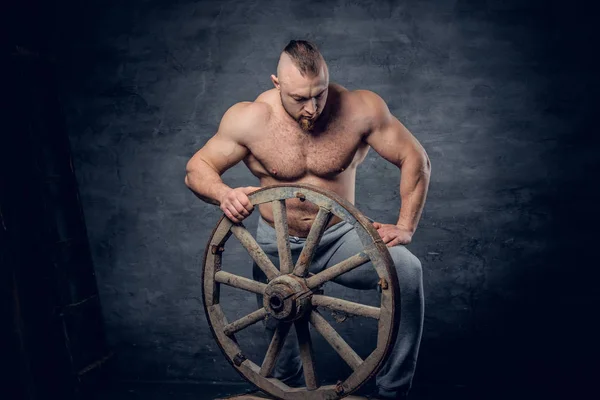 Hunk man holds holds wooden wheel