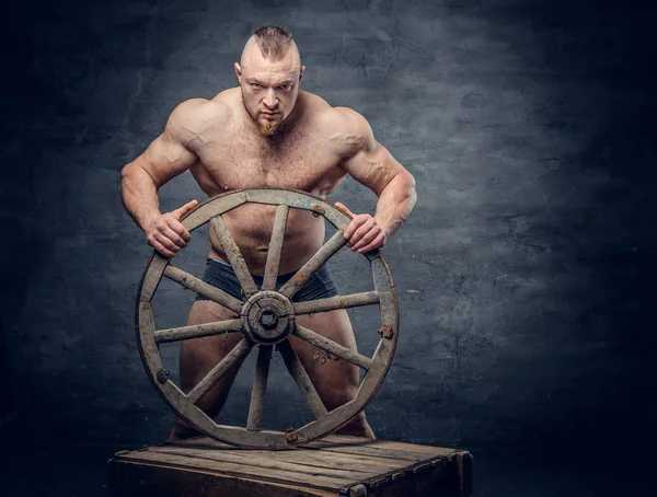 Uomo senza maglietta tiene ruota in legno — Foto Stock