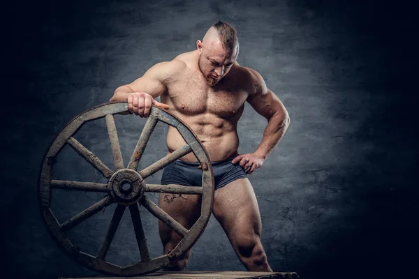 El hombre sin camisa sostiene la rueda de madera — Foto de Stock