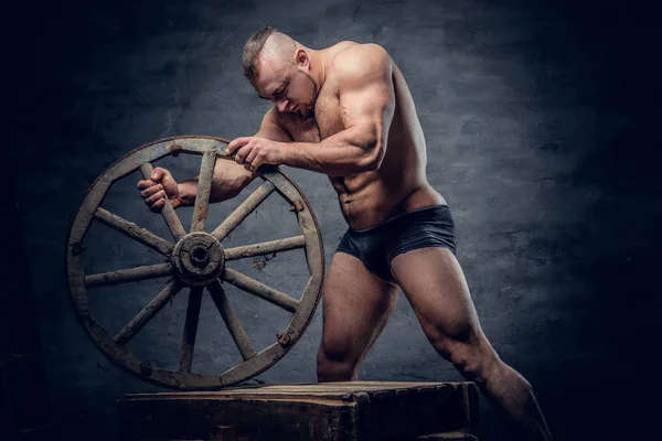 Bodybuilder innehar gamla trä hjulet — Stockfoto