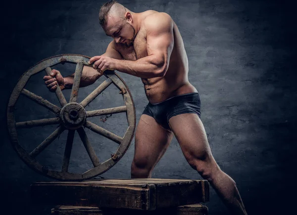 Shirtless man holds wooden wheel — Stock Photo, Image