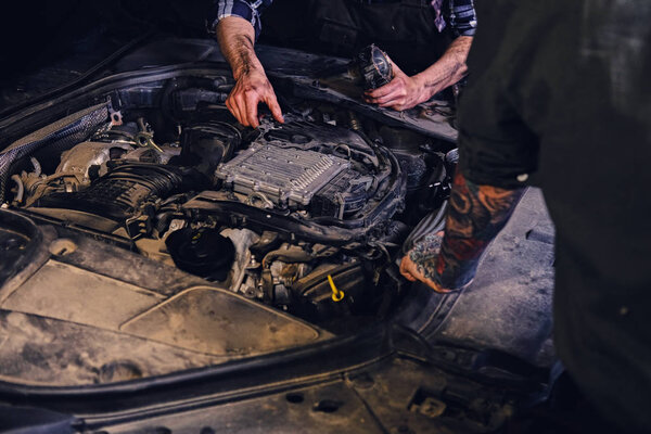 Two mechanics fixing car's engine 