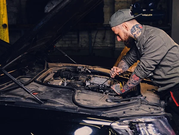 Mecánico tatuado cerca de coche en un taller — Foto de Stock