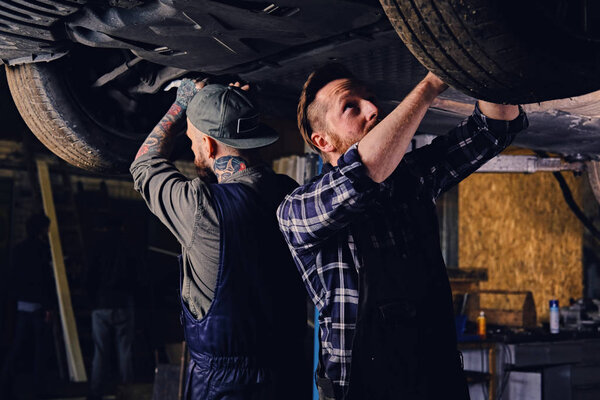 Bearded mechanics working under the car