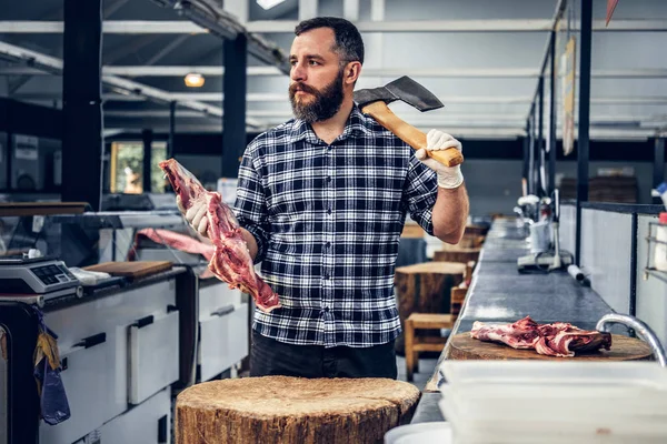 Meatman detém um machado e carne fresca — Fotografia de Stock