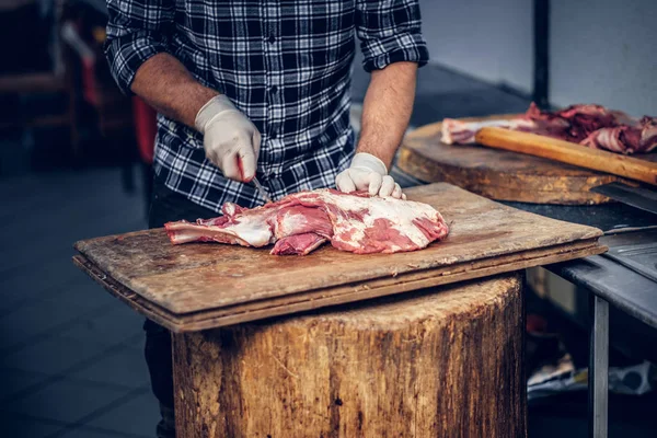 Açougueiro barbudo cortar bacon fresco — Fotografia de Stock