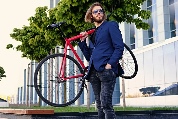Um homem segura a bicicleta vermelha em seu ombro — Fotografia de Stock