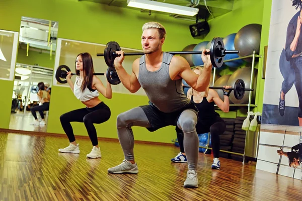 Man en twee vrouwen doen squats — Stockfoto