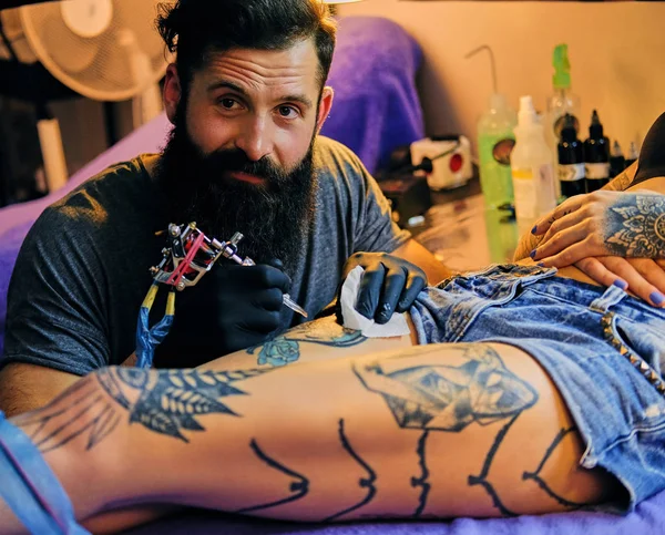 Bebaarde tatoeëerder maakt een tatoeage — Stockfoto