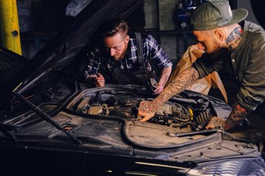 Tattooed mechanics fixing car's engine clipart